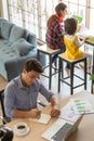 Mixed race family stays at home together, father works at desk with graph and charts and a laptop notebook computer while mother Royalty Free Stock Photo