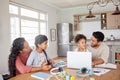 Mixed race family using information technology at home. Two little girls doing homework in the kitchen with help from Royalty Free Stock Photo