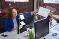 Mixed race female in front of computers separated by sneeze shield giving document to colleague