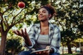 Mixed race female holding digital tablet researching project on healthy foods while playing with fresh red tomato