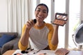 Mixed race gender fluid man making vlog holding foundation powder makeup and brush, smiling Royalty Free Stock Photo