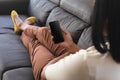 Mixed race gender fluid man relaxing at home on couch using smartphone, with copy space screen Royalty Free Stock Photo