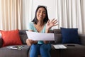 Mixed race gender fluid man working at home making video call holding documents, smiling and waving Royalty Free Stock Photo