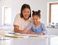 Mixed race girl learning and studying in homeschool with mom. Woman helping daughter with homework and assignments at Royalty Free Stock Photo