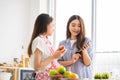 Mixed race girl younger and older sister talk and smile while play and using smartphone inside of the kitchen in the morning while