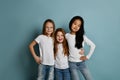 Mixed race international kids girls happy best friends in jeans and white t-shirts stand together hugging smiling Royalty Free Stock Photo