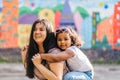 Mixed race laughing ecuadorian mother playing and carrying young preschooler dark-skinned daughter on her shoulders Royalty Free Stock Photo