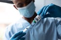 Mixed race male doctor holding covid-19 vaccination wearing face mask