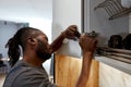 Mixed-race man fixing white cupboard door using spanner Royalty Free Stock Photo