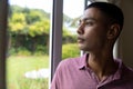 Mixed race man looking through window and thinking Royalty Free Stock Photo