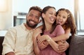 Mixed race parents enjoying weekend with daughter in home living room. Smiling hispanic girl hugging and bonding with Royalty Free Stock Photo