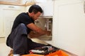 Mixed race plumber fixing the kitchen sink in a home Royalty Free Stock Photo