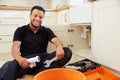 Mixed race plumber sitting in a kitchen, portrait Royalty Free Stock Photo