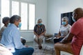 Mixed race senior female counsellor in face mask advising diverse group of senior friends Royalty Free Stock Photo