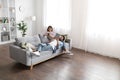 Mixed race spouses resting on sofa at home, using gadgets Royalty Free Stock Photo