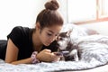 Mixed race teenage girl using cell phone with chihuahua dog next to her side in bed. Royalty Free Stock Photo