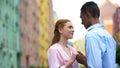 Mixed-race teenager tenderly holding hand of girl saying compliments, date