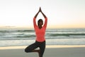 Mixed race woman on beach practicing yoga at sunset Royalty Free Stock Photo