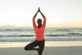 Mixed race woman on beach practicing yoga during sunset Royalty Free Stock Photo