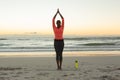 Mixed race woman on beach practicing yoga during sunset Royalty Free Stock Photo