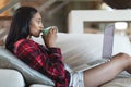 Mixed race woman drinking coffee using laptop computer at home Royalty Free Stock Photo