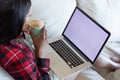 Mixed race woman drinking coffee and using laptop at home Royalty Free Stock Photo