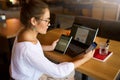 Mixed race woman in glasses working with multiple electronic internet devices. Freelancer businesswoman has tablet and