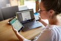 Mixed race woman in glasses working with multiple electronic internet devices. Freelancer businesswoman has tablet and