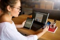 Mixed race woman in glasses working with multiple electronic internet devices. Freelancer businesswoman has tablet and