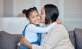 Mixed race woman kissing her adorable little daughter on the cheek while bonding together at home. Small girl feeling Royalty Free Stock Photo