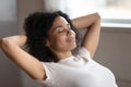 Mixed race woman putting hands behind head resting indoors