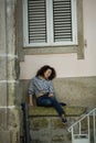 A mixed-race woman sitting near the wall of the house in Porto Royalty Free Stock Photo