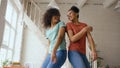 Mixed race young beautiful girls dancing on a bed together having fun leisure in bedroom at home Royalty Free Stock Photo