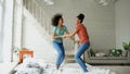 Mixed race young beautiful girls dancing on a bed together having fun leisure in bedroom at home Royalty Free Stock Photo