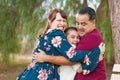 Mixed Race Young Family Hugging At The Park