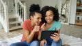 Cheerful mixed race young funny girls talking online video chat on tablet computer with their friends at home Royalty Free Stock Photo