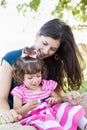 Mixed Race Young Mother and Cute Baby Girl Applying Fingernail Polish