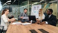 Mixed races coworkers analysing different business papers and working with computers at the tables in modern office. Royalty Free Stock Photo