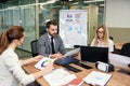 Mixed races coworkers analysing different business papers and working with computers at the tables in modern office. Royalty Free Stock Photo