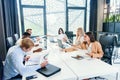 Mixed races coworkers analysing different business papers and working with computers at the tables in modern office. Royalty Free Stock Photo