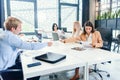 Mixed races coworkers analysing different business papers and working with computers at the tables in modern office. Royalty Free Stock Photo