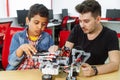 Mixed Racial group of School children controlling robotic machine with remote control together teacher. Creative kids