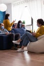 Mixed racial people sitting together in living room browsing on phones