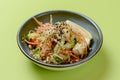 Mixed salad with mixed greens, cucumber, brocolli, sesame seeds and carrots served in a bowl on bright green background