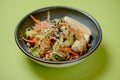 Mixed salad with mixed greens, cucumber, brocolli, sesame seeds and carrots served in a bowl on bright green background