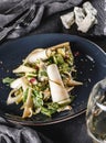 Mixed salad with pear, cheese gorgonzola and sea buckthorn sauce in a ceramic plate over grey background. Healthy vegan food, Royalty Free Stock Photo