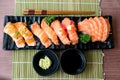 Mixed salmon sushi and sashimi on black plate along with Japanese sauce and green leaf decoration, Japanese food, close up at Royalty Free Stock Photo