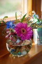Mixed spring bouquet with Viola, Gerbera and blooming trees branches in a mini glass vase on the window