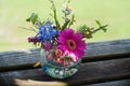 Mixed spring bouquet with Viola, Gerbera and blooming trees branches in a mini glass vase on the wooden background