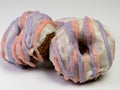 Mixed strawberry blueberry doughnut / donut covered in white glaze with pink and purple stripes of glaze on a white background.
